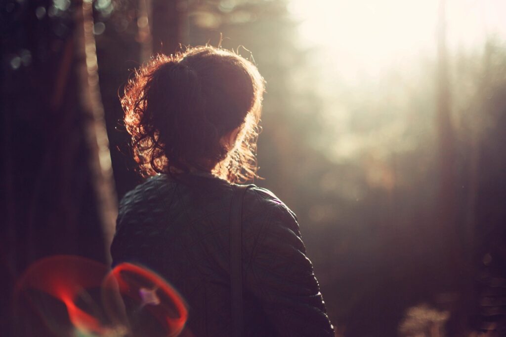 Understanding Mental Health - Person Female looking into the distance in thought. In woodland scene.